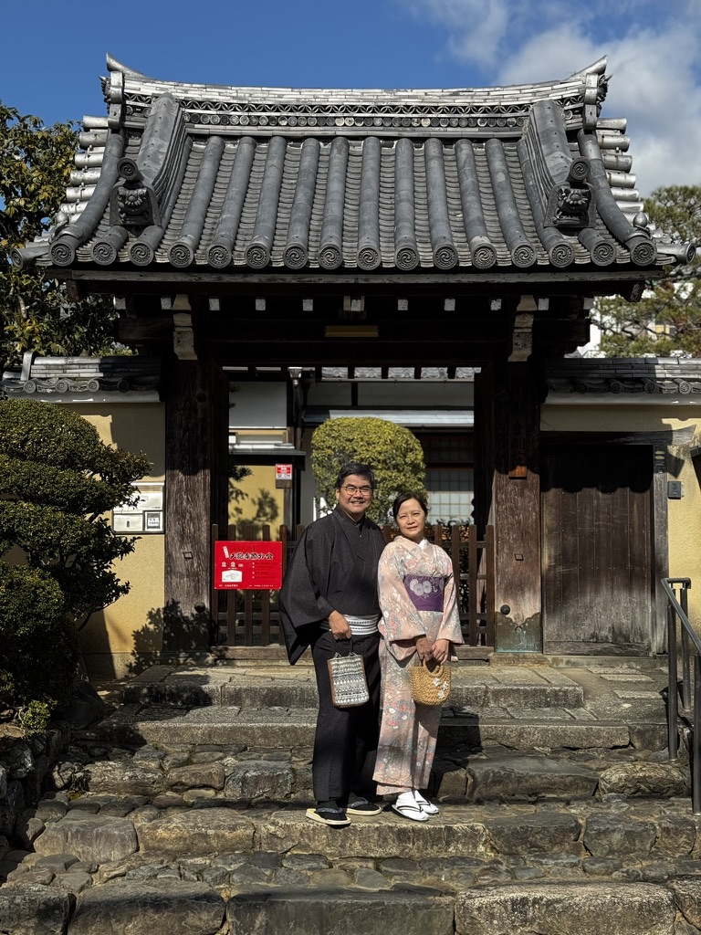 Parents wearing kimonos in front of a traditional Kyoto temple gate