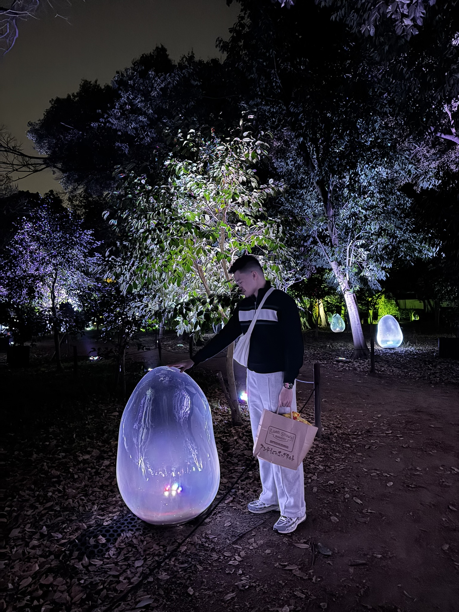 Portrait with a glowing egg-shaped light installation at Osaka Botanic Garden