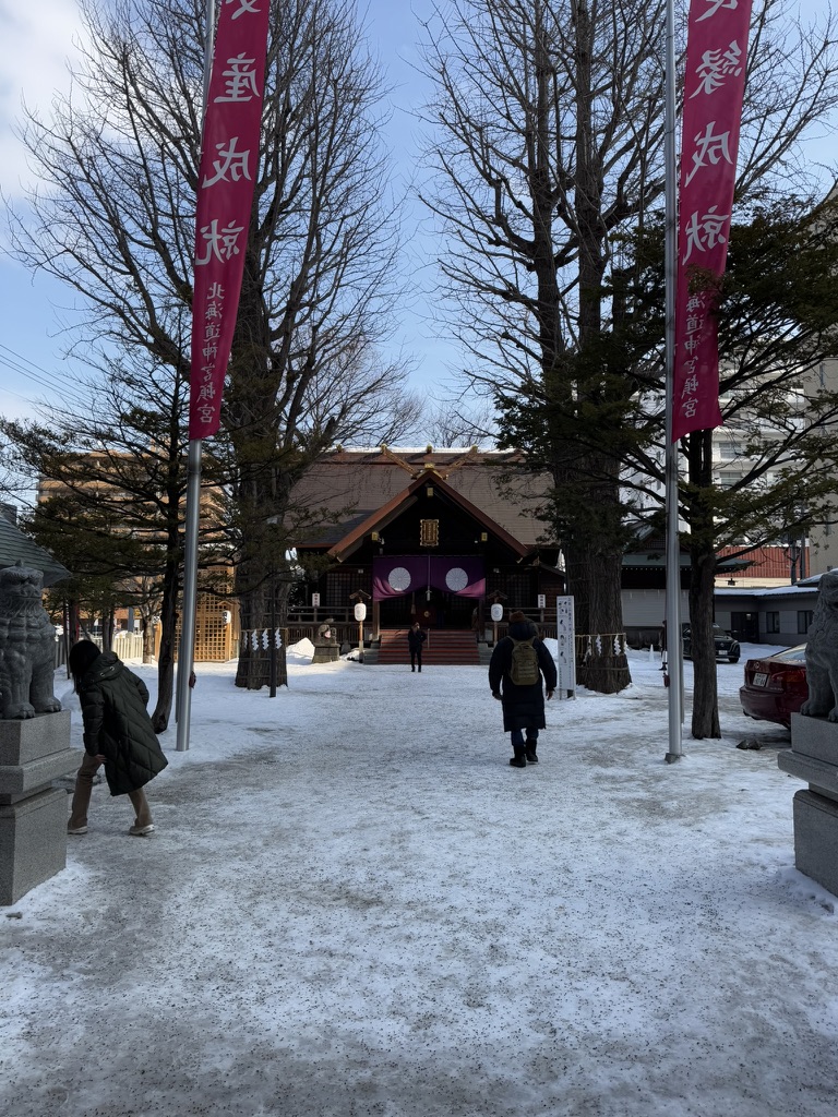 Snowy approach to Hokkaido Jingu Shrine with red banners