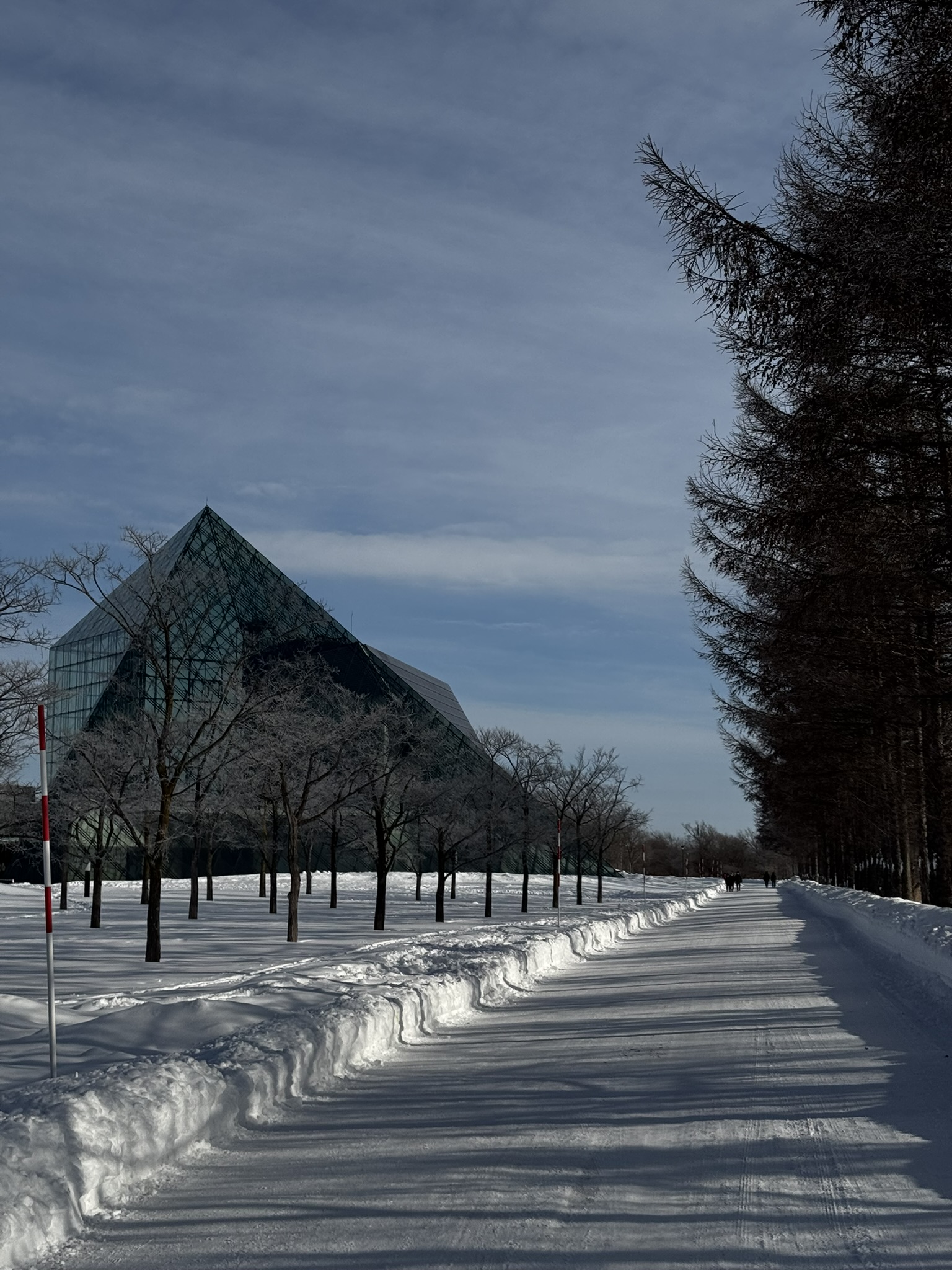 Snowy road leading toward the glass pyramid at Moerenuma Park