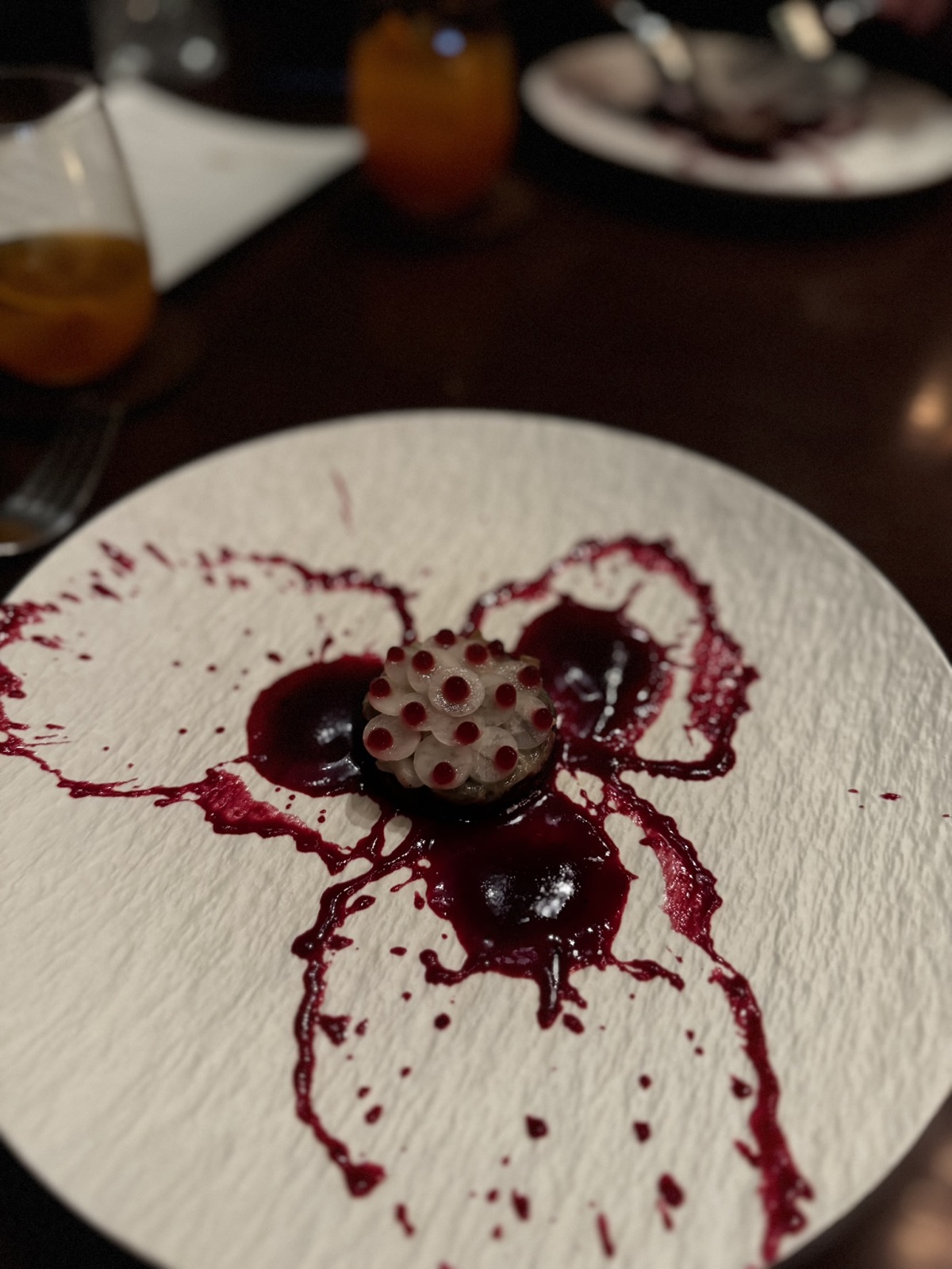 A red-toned Saawaan course plated in a dark bowl