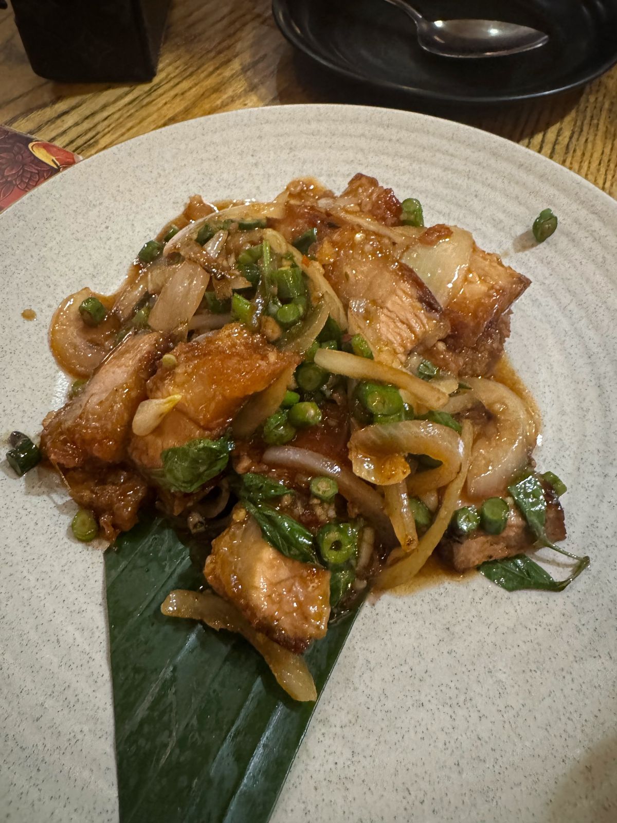 Plate of stir-fried pork with green chillies on a banana leaf