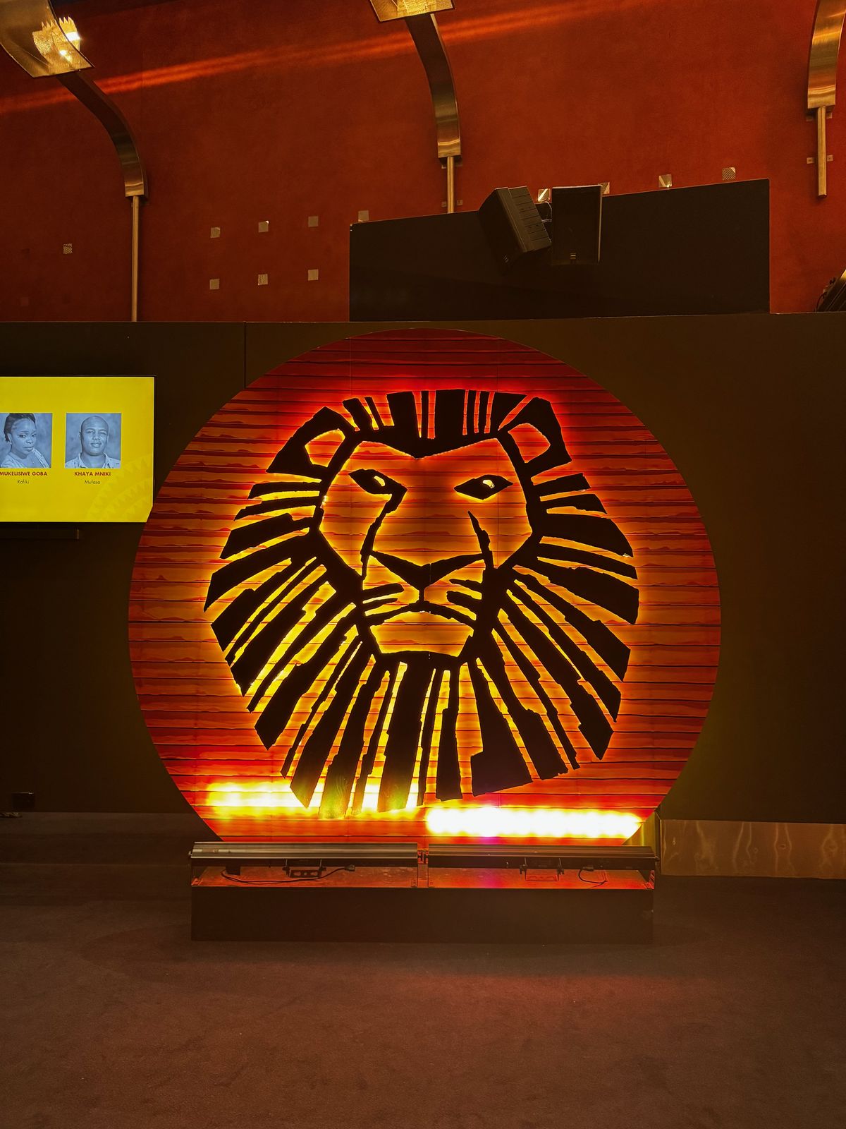 Illuminated Lion King lion mask artwork in a theatre foyer
