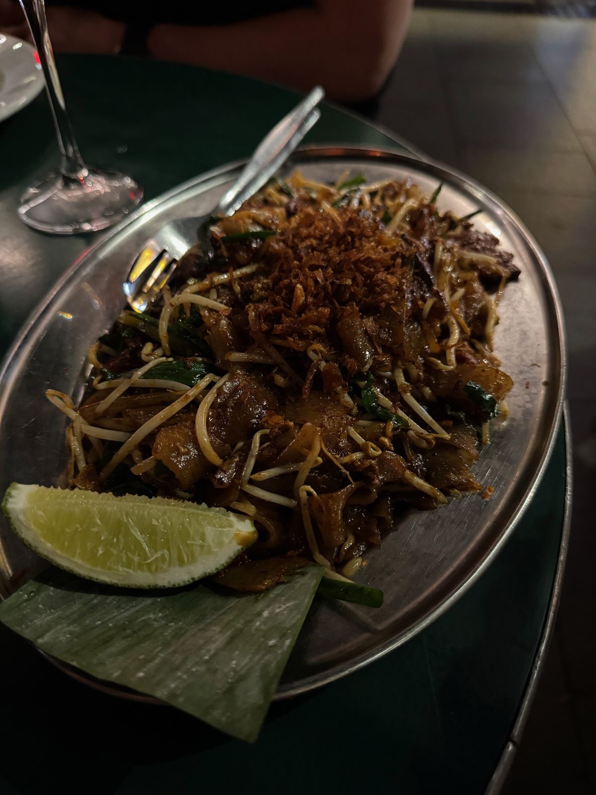 Plate of char-fried flat noodles with lime and banana leaf at MuMu