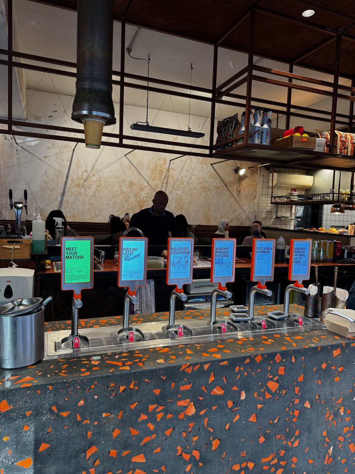 Coffee bar with terrazzo counter and a barista working at the machines