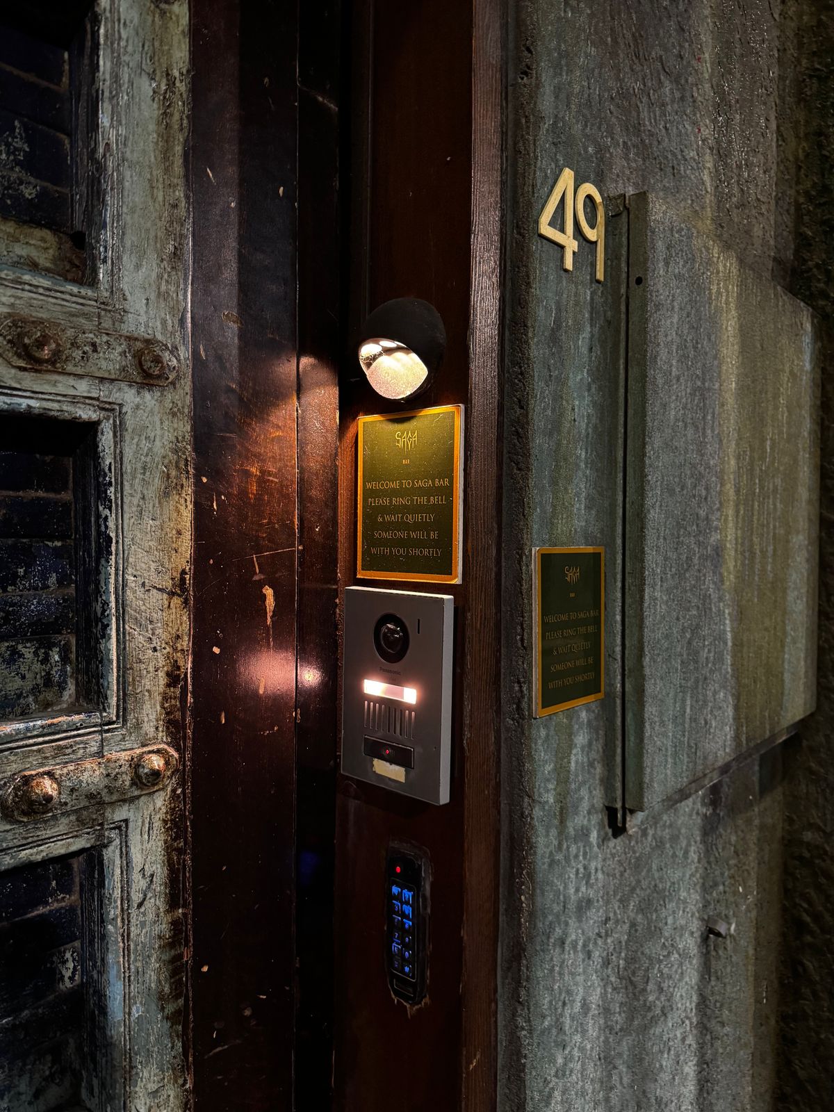 Unmarked dark doorway numbered 49 with an intercom panel at night
