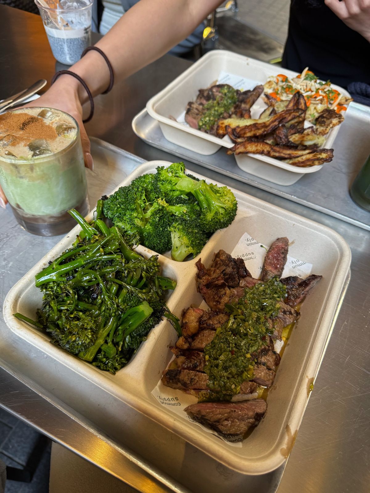 Takeaway tray of sliced steak with chimichurri and charred broccolini