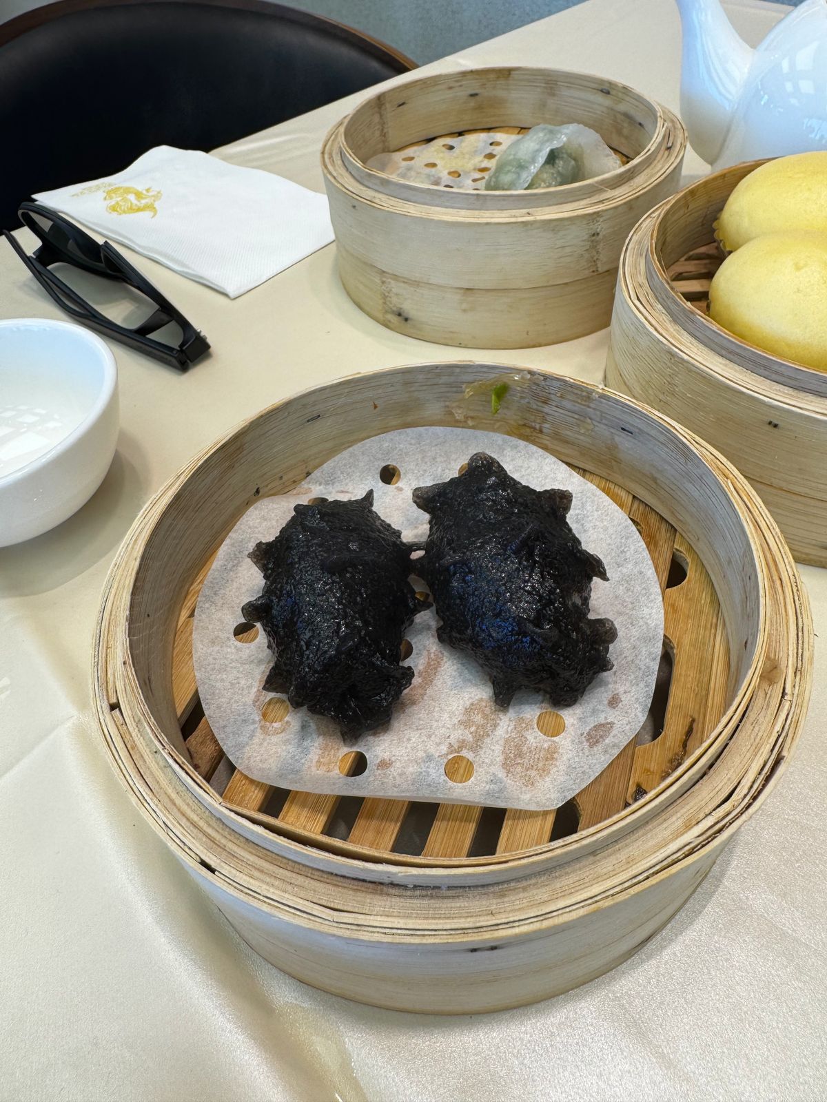 Steamer basket of black squid-ink dumplings shaped like small parcels