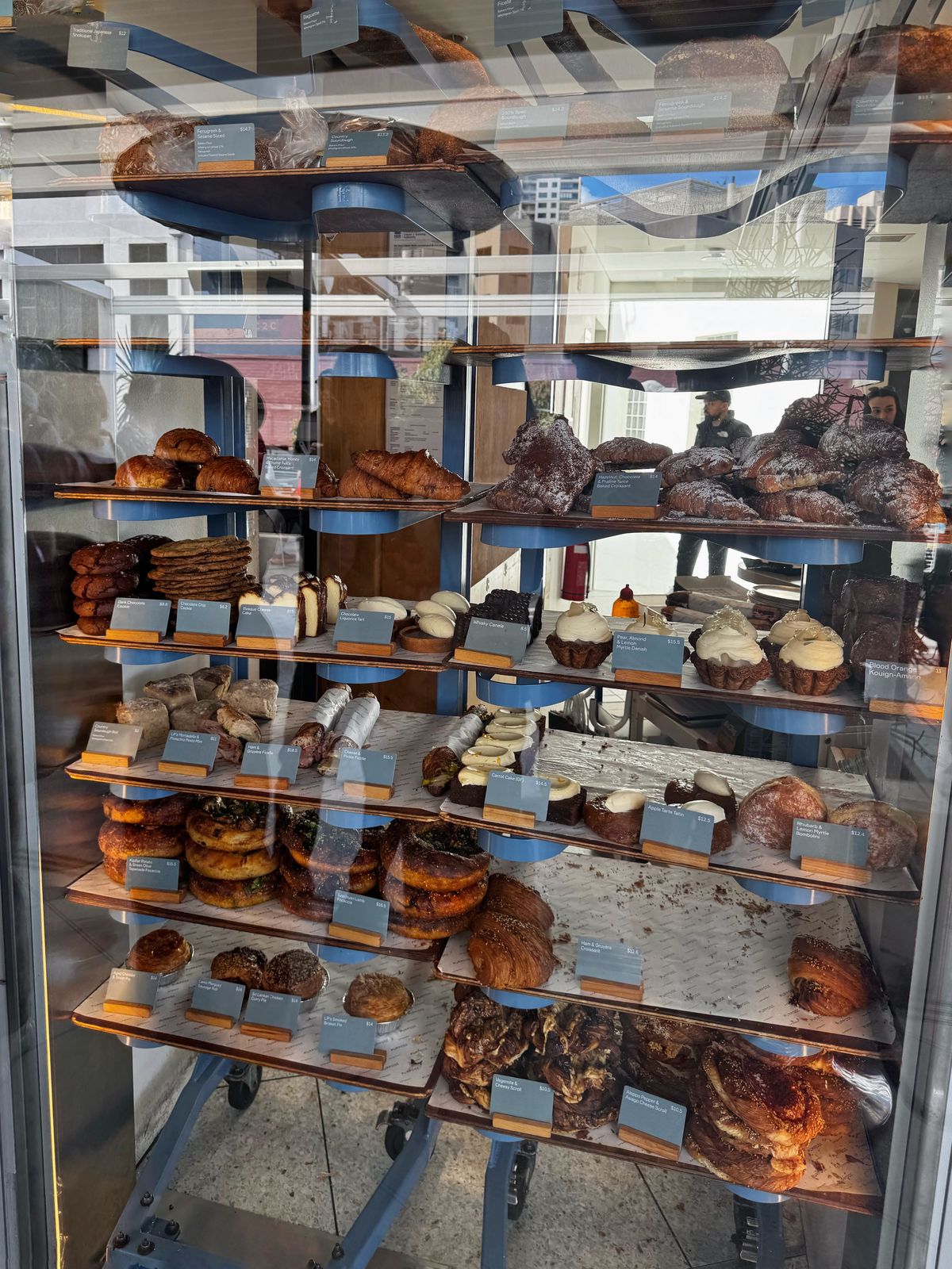 Trolley rack of croissants, danishes and pastries behind glass