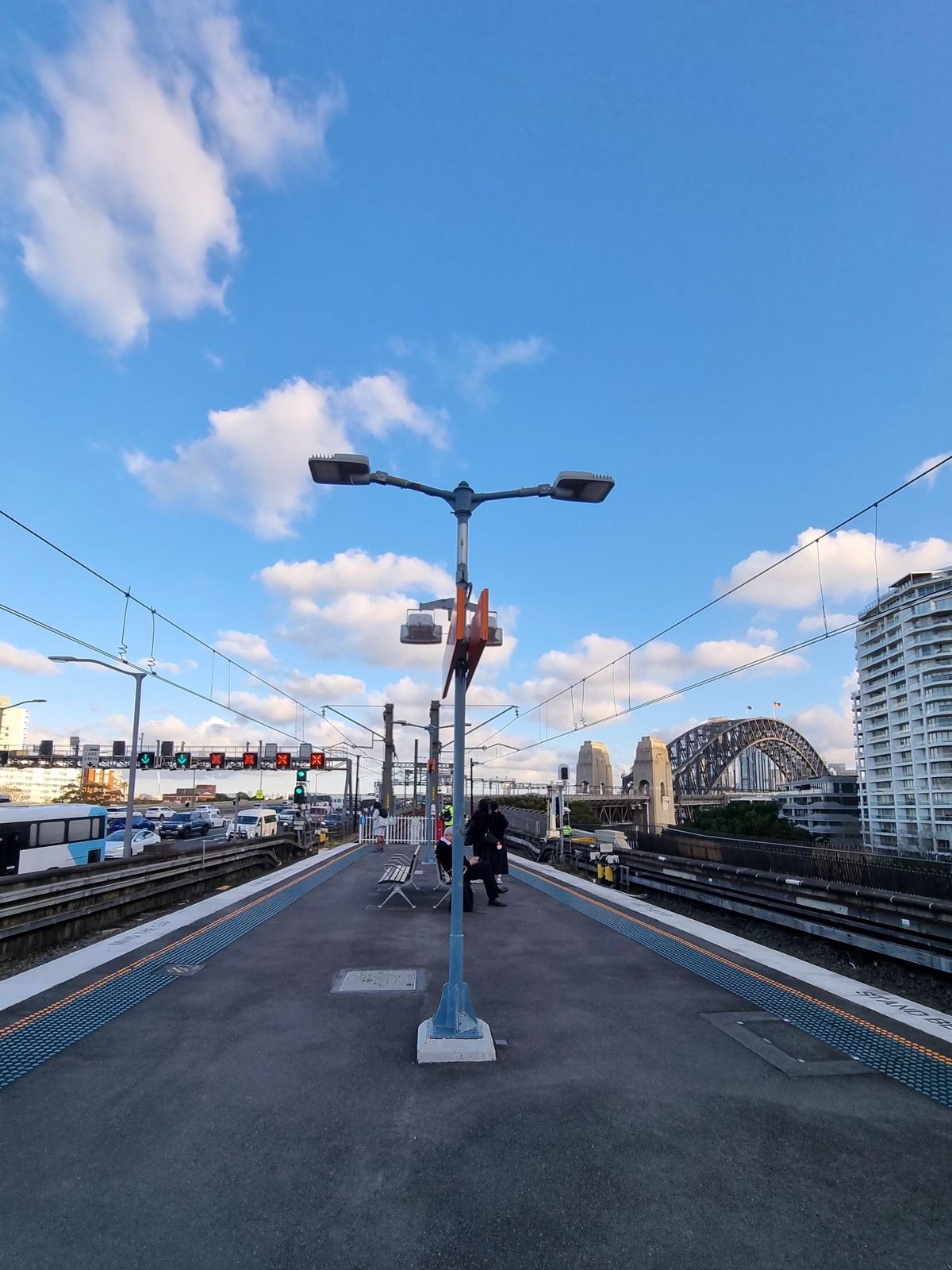Empty Sydney train platform in morning light with the Harbour Bridge in the distance