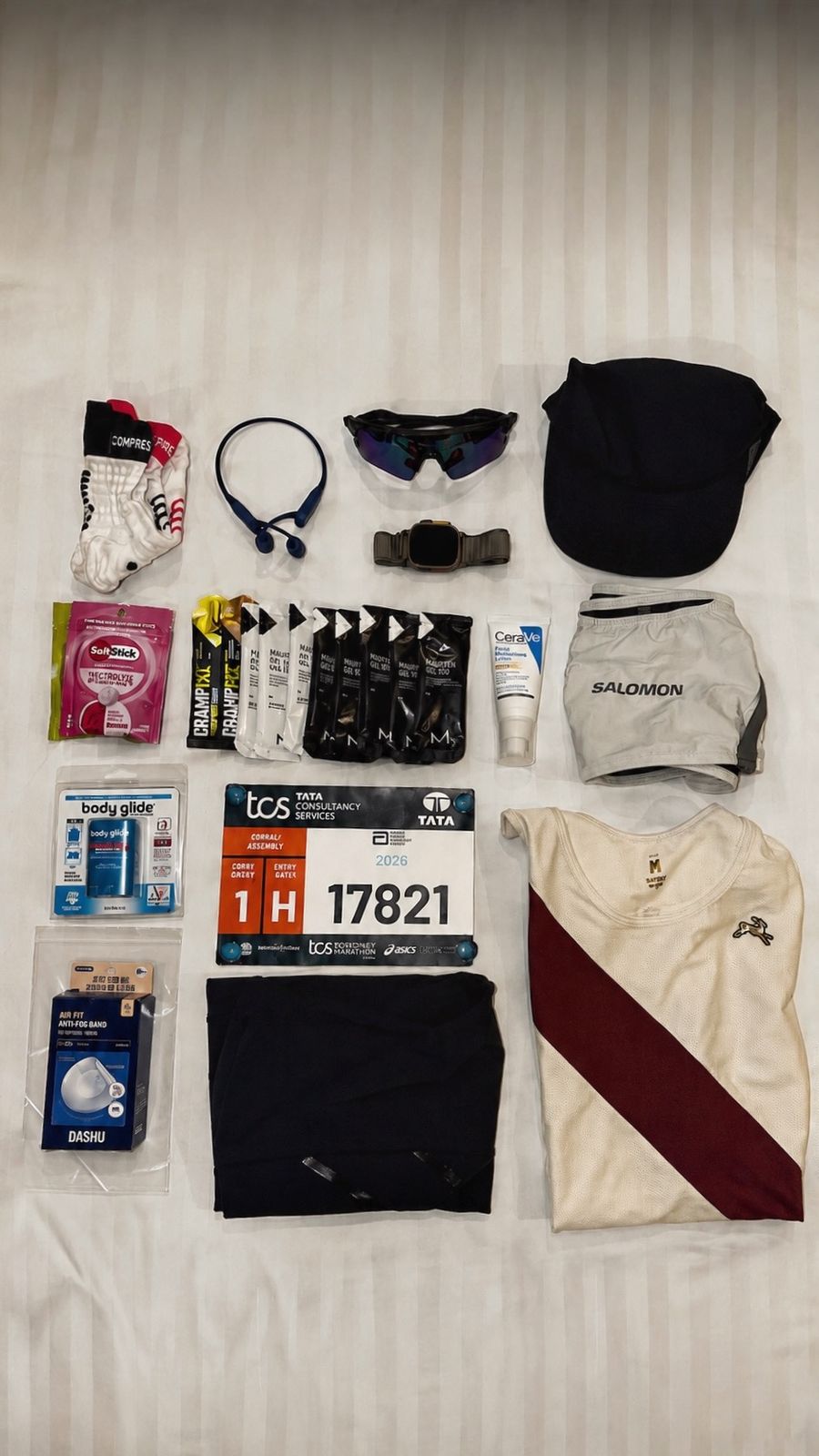 Race kit laid out on a hotel bed: singlet, shorts, cap, sunglasses, gels and race bib 17821