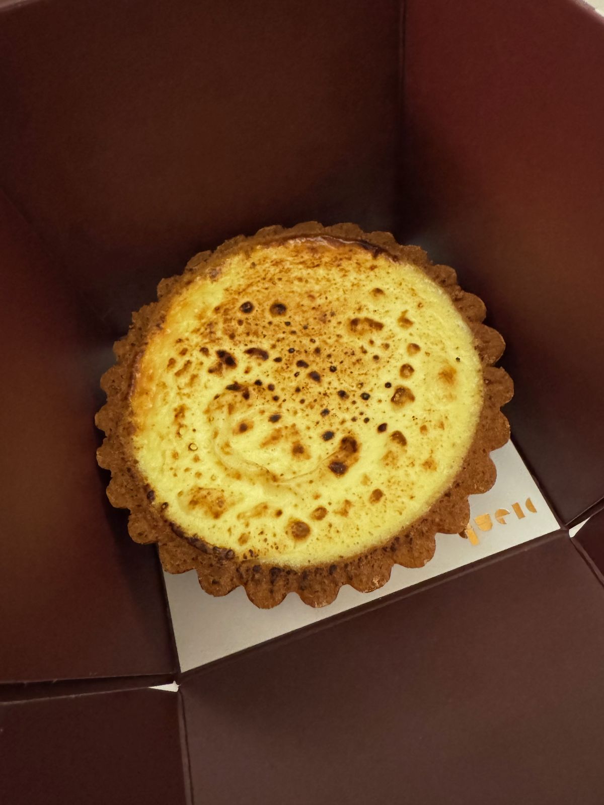 Golden custard tart in an open box on a bed at night