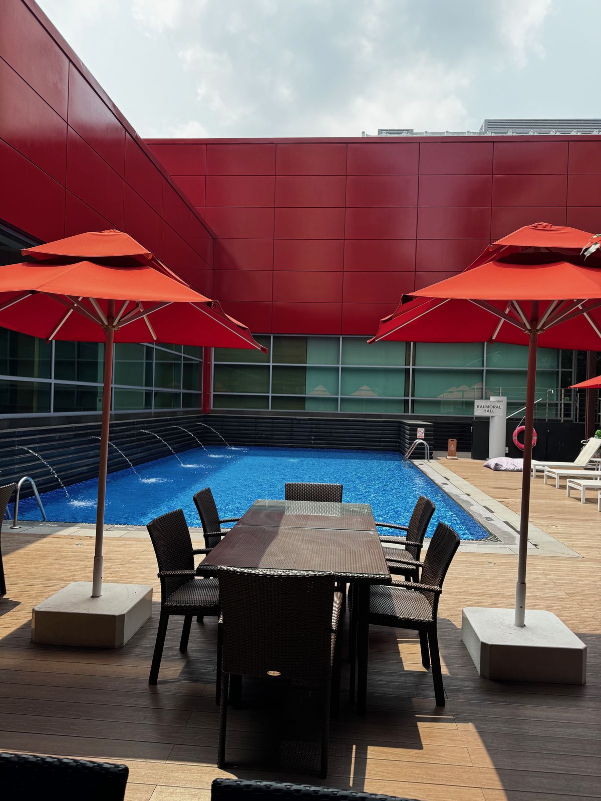 Rooftop hotel pool with red umbrellas and empty poolside tables