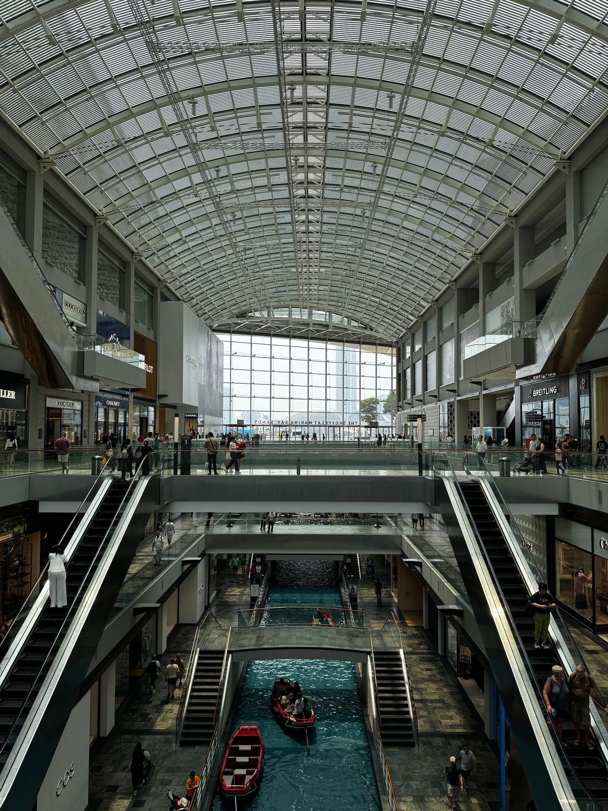 The canal, escalators and glass roof inside the Shoppes at Marina Bay Sands