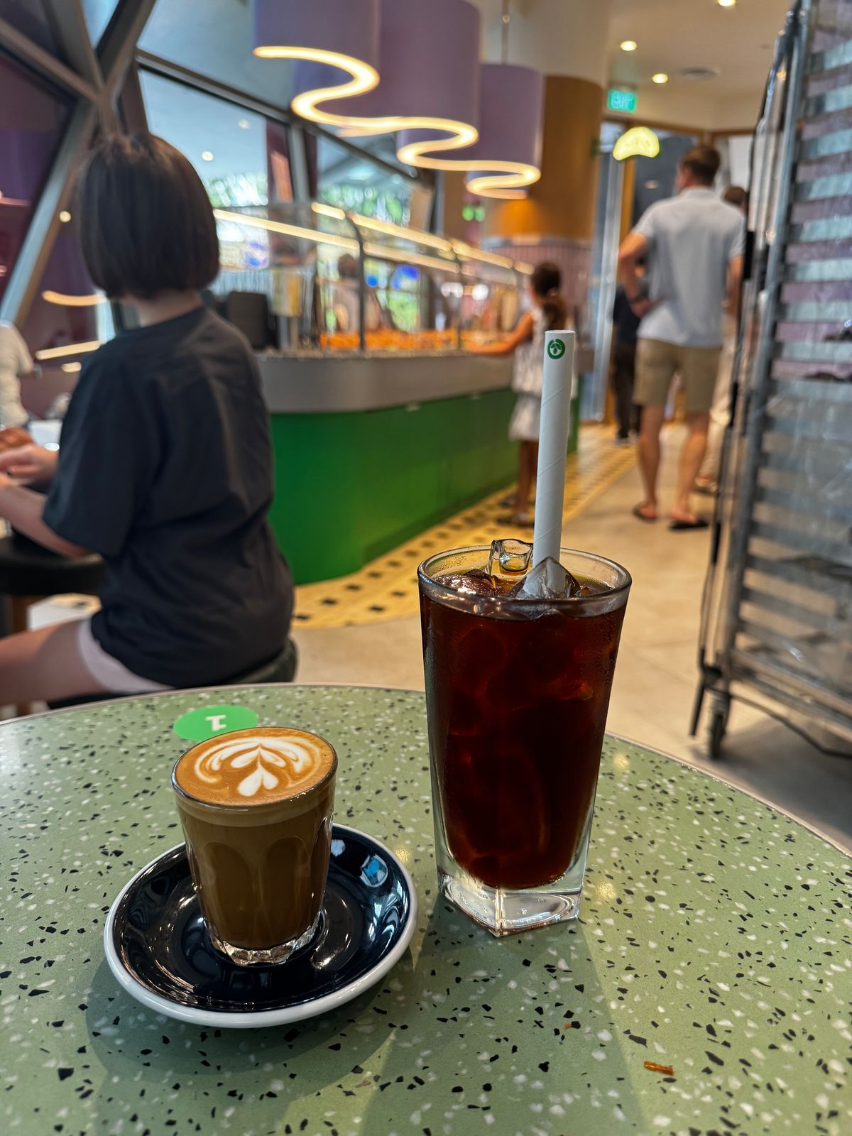 Flat white and an iced black coffee on a green terrazzo table