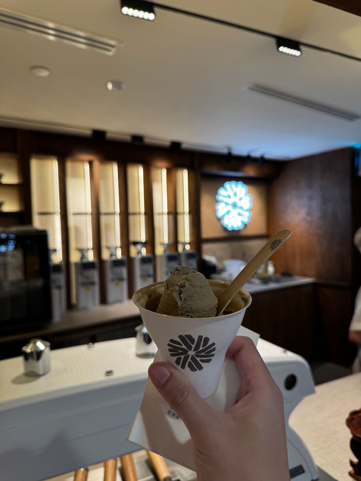 Cup of matcha soft serve held up inside a dessert shop